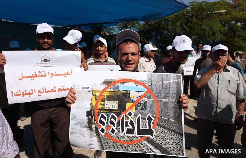 Palestinian owners of factories hold banners during a protest against israeli blockade on operations their factories, in front of the headquarter United Nation "UNSCO", in Gaza city, on October 4, 2016. Photo by Ashraf A...