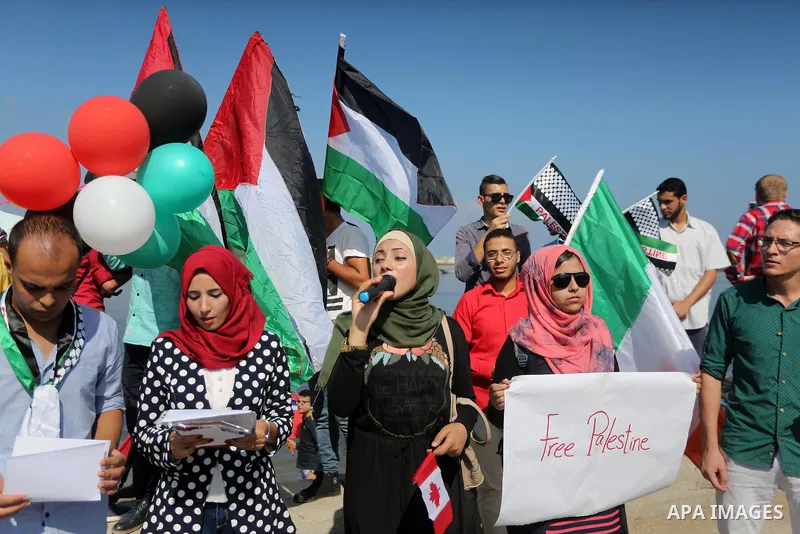 Palestinian youths hold banners during a rally to show solidarity with ship called “Zaytouna” set to arrive in Gaza, at the Seaport of Gaza City October 5, 2016. Photo by Mohammed Asad