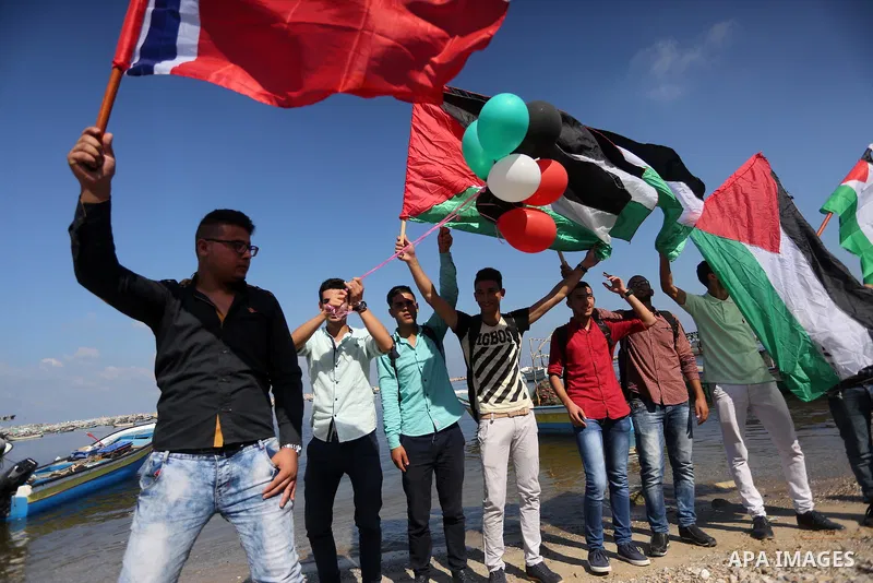 Palestinian youths hold banners during a rally to show solidarity with ship called “Zaytouna” set to arrive in Gaza, at the Seaport of Gaza City October 5, 2016. Photo by Mohammed Asad