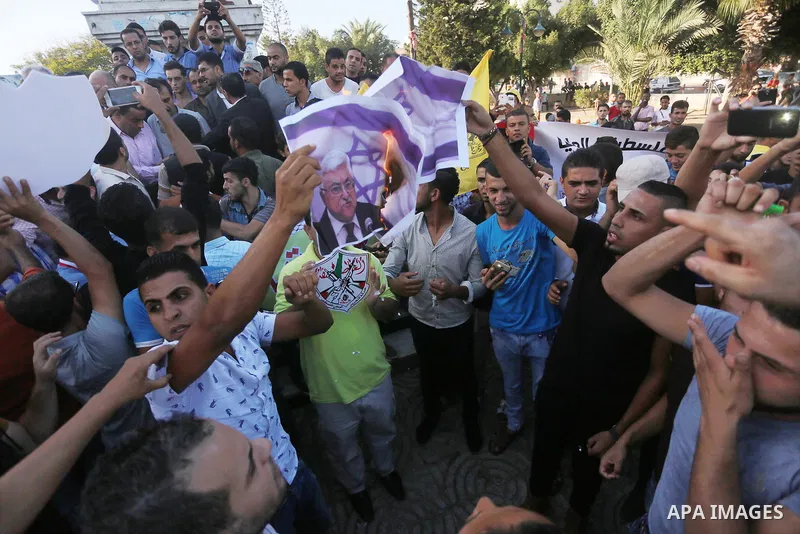 Palestinians who support Palestinian senior Fatah official Mohammed Dahlan burn crossed posters of Palestinian President Mahmoud Abbas and Israeli flags during a protest in Gaza City on Oct. 06, 2016. Photo by Mohammed A...