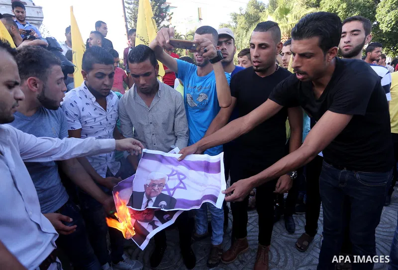 Palestinians who support Palestinian senior Fatah official Mohammed Dahlan burn crossed posters of Palestinian President Mahmoud Abbas and Israeli flags during a protest in Gaza City on Oct. 06, 2016. Photo by Mohammed A...