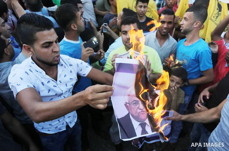 Palestinians who support Palestinian senior Fatah official Mohammed Dahlan burn crossed posters of Palestinian President Mahmoud Abbas and Israeli flags during a protest in Gaza City on Oct. 06, 2016. Photo by Mohammed A...