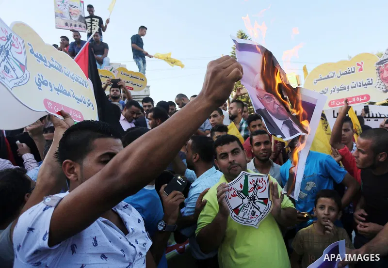 Palestinians who support Palestinian senior Fatah official Mohammed Dahlan burn crossed posters of Palestinian President Mahmoud Abbas and Israeli flags during a protest in Gaza City on Oct. 06, 2016. Photo by Mohammed A...