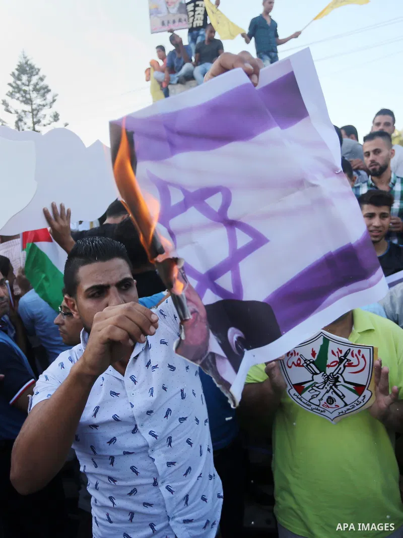 Palestinians who support Palestinian senior Fatah official Mohammed Dahlan burn crossed posters of Palestinian President Mahmoud Abbas and Israeli flags during a protest in Gaza City on Oct. 06, 2016. Photo by Mohammed A...