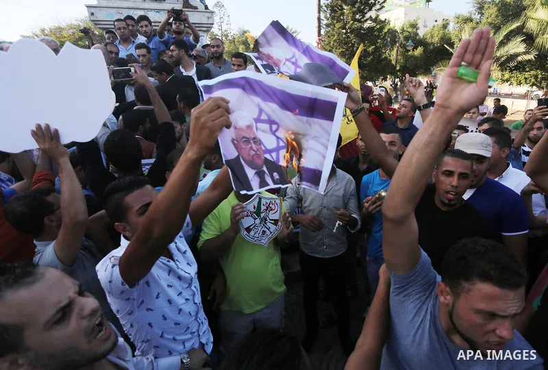 Palestinians who support Palestinian senior Fatah official Mohammed Dahlan burn crossed posters of Palestinian President Mahmoud Abbas and Israeli flags during a protest in Gaza City on Oct. 06, 2016. Photo by Mohammed A...