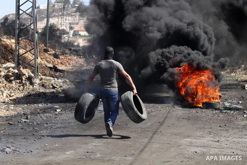A Palestinian protester burns tires during clashes with Israeli security forces following a weekly demonstration against the expropriation of Palestinian land by Israel on October 6, 2016, in the village of Kfar Qaddum,...