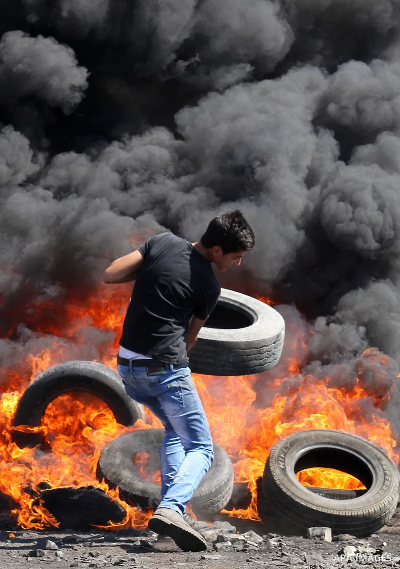 A Palestinian protester burns tires during clashes with Israeli security forces following a weekly demonstration against the expropriation of Palestinian land by Israel on October 6, 2016, in the village of Kfar Qaddum,...