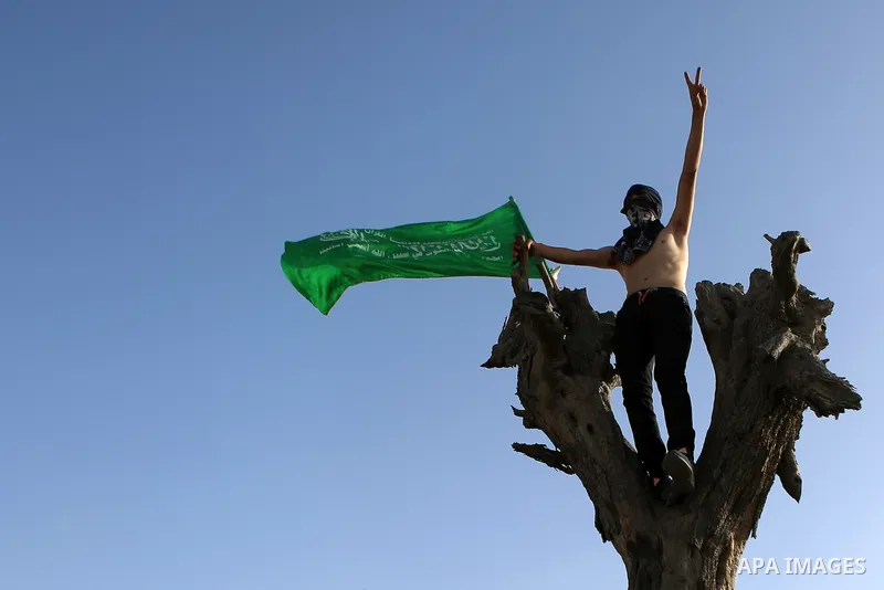 A Palestinian protester waves a Hamas flag during clashes with Israeli border policemen in the West Bank town of Al-Ram, near Jerusalem October 9, 2016. A Palestinian opened fire from a car in Jerusalem on Sunday and aga...
