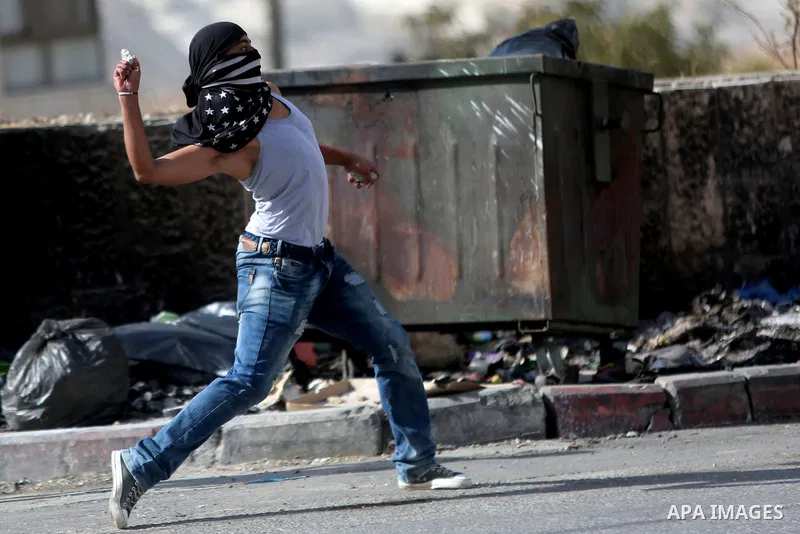 A Palestinian protester hurls stones towards Israeli border policemen during clashes in the West Bank town of Al-Ram, near Jerusalem October 9, 2016. A Palestinian opened fire from a car in Jerusalem on Sunday and again...