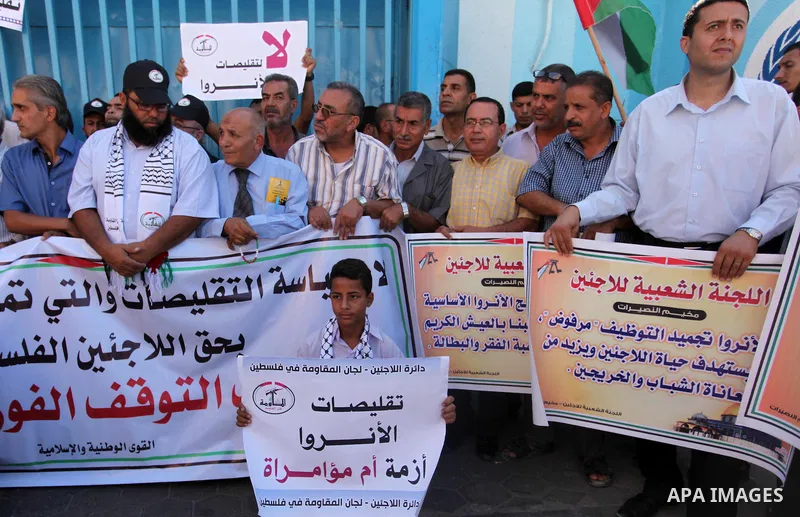 Palestinians hold banners during a protest against the UNRWA decision to reduce of the aid in front of the headquarters United Nations Relief and Works Agency (UNRWA), in Gaza city on October 11, 2016. Photo by Ashraf Am...