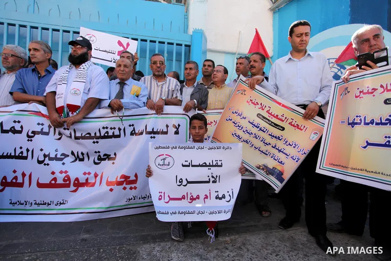 Palestinians hold banners during a protest against the UNRWA decision to reduce of the aid in front of the headquarters United Nations Relief and Works Agency (UNRWA), in Gaza city on October 11, 2016. Photo by Ashraf Am...