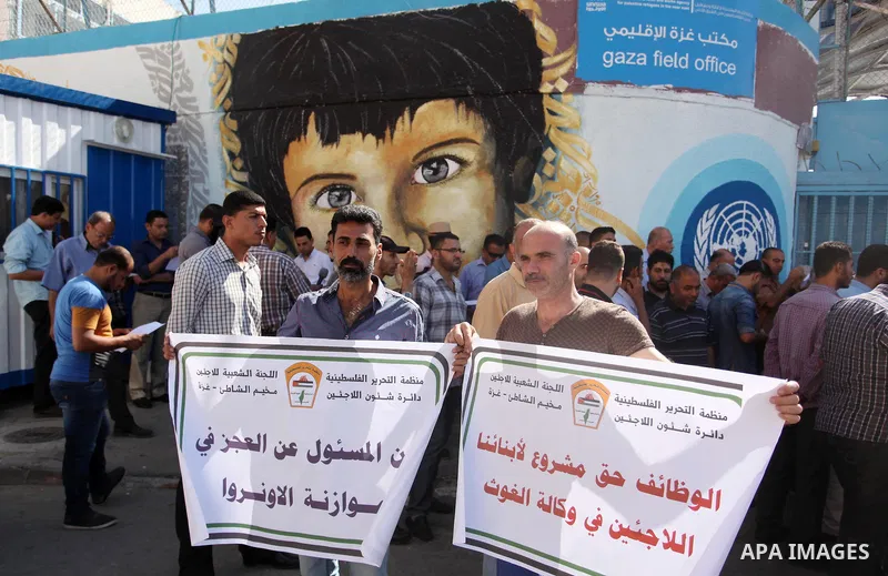 Palestinians hold banners during a protest against the UNRWA decision to reduce of the aid in front of the headquarters United Nations Relief and Works Agency (UNRWA), in Gaza city on October 11, 2016. Photo by Ashraf Am...
