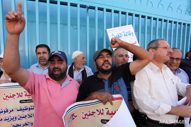 Palestinians hold banners during a protest against the UNRWA decision to reduce of the aid in front of the headquarters United Nations Relief and Works Agency (UNRWA), in Gaza city on October 11, 2016. Photo by Ashraf Am...