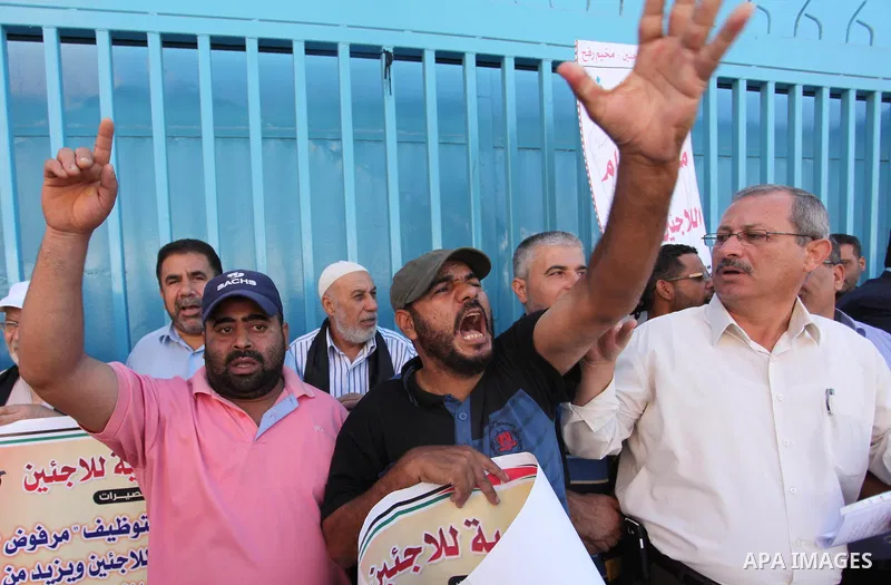 Palestinians hold banners during a protest against the UNRWA decision to reduce of the aid in front of the headquarters United Nations Relief and Works Agency (UNRWA), in Gaza city on October 11, 2016. Photo by Ashraf Am...