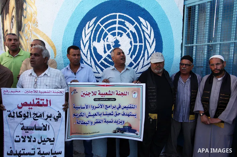 Palestinians hold banners during a protest against the UNRWA decision to reduce of the aid in front of the headquarters United Nations Relief and Works Agency (UNRWA), in Gaza city on October 11, 2016. Photo by Ashraf Am...