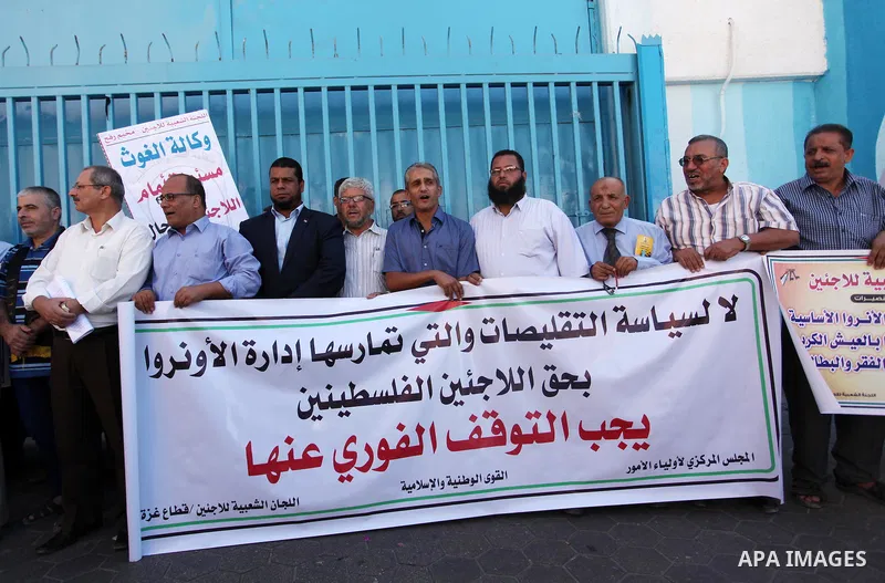 Palestinians hold banners during a protest against the UNRWA decision to reduce of the aid in front of the headquarters United Nations Relief and Works Agency (UNRWA), in Gaza city on October 11, 2016. Photo by Ashraf Am...