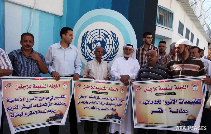 Palestinians hold banners during a protest against the UNRWA decision to reduce of the aid in front of the headquarters United Nations Relief and Works Agency (UNRWA), in Gaza city on October 11, 2016. Photo by Ashraf Am...