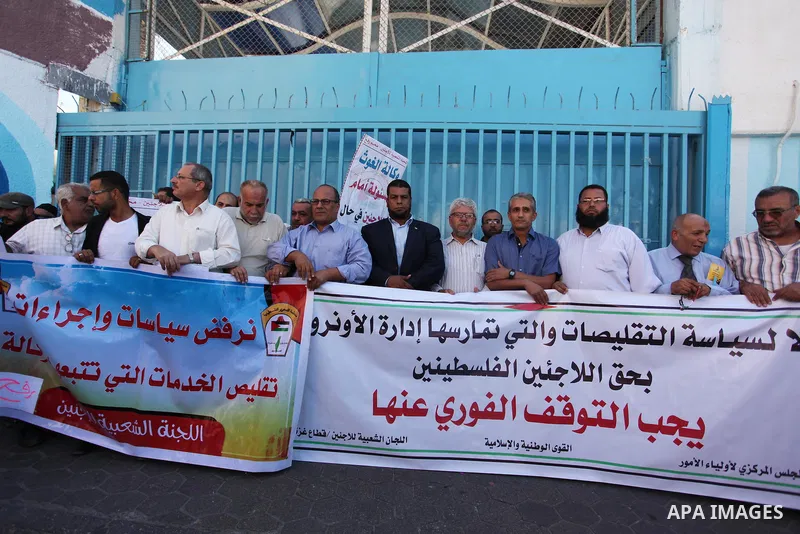 Palestinians hold banners during a protest against the UNRWA decision to reduce of the aid in front of the headquarters United Nations Relief and Works Agency (UNRWA), in Gaza city on October 11, 2016. Photo by Ashraf Am...