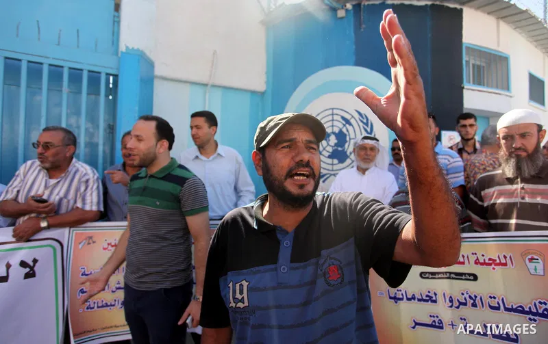 Palestinians hold banners during a protest against the UNRWA decision to reduce of the aid in front of the headquarters United Nations Relief and Works Agency (UNRWA), in Gaza city on October 11, 2016. Photo by Ashraf Am...