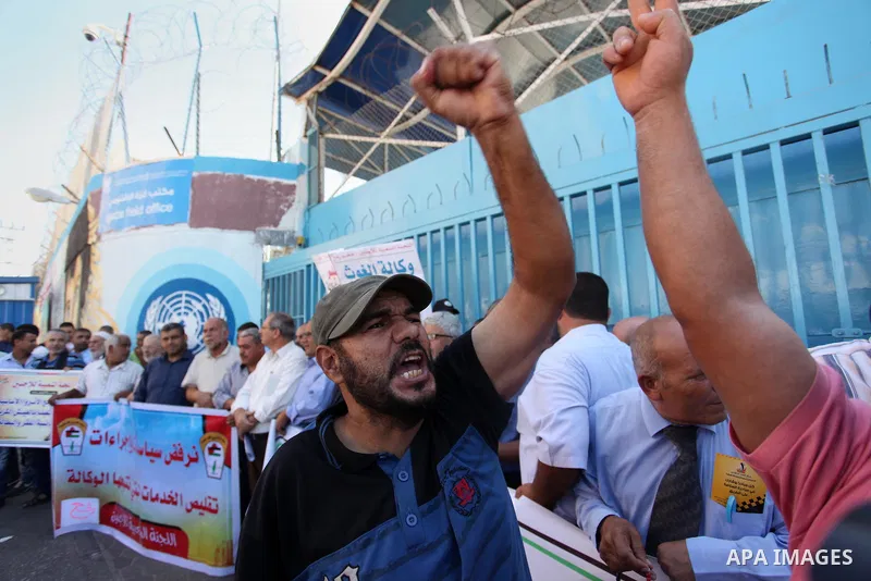 Palestinians hold banners during a protest against the UNRWA decision to reduce of the aid in front of the headquarters United Nations Relief and Works Agency (UNRWA), in Gaza city on October 11, 2016. Photo by Ashraf Am...