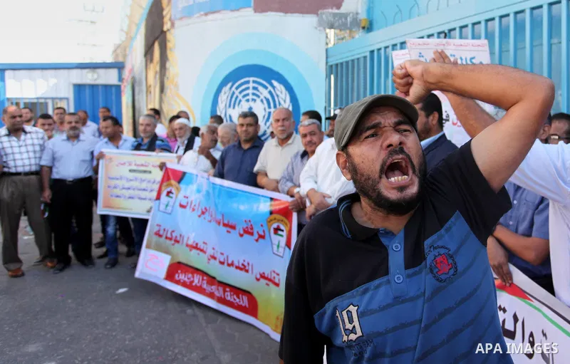 Palestinians hold banners during a protest against the UNRWA decision to reduce of the aid in front of the headquarters United Nations Relief and Works Agency (UNRWA), in Gaza city on October 11, 2016. Photo by Ashraf Am...