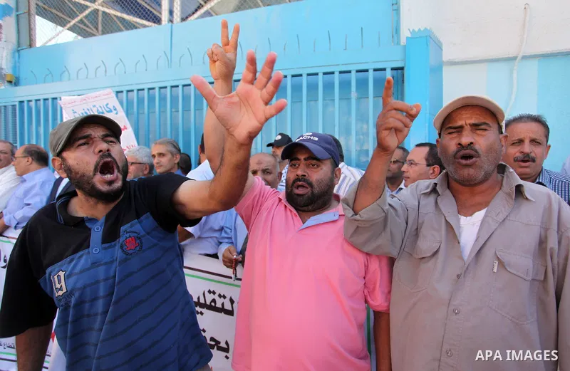 Palestinians hold banners during a protest against the UNRWA decision to reduce of the aid in front of the headquarters United Nations Relief and Works Agency (UNRWA), in Gaza city on October 11, 2016. Photo by Ashraf Am...