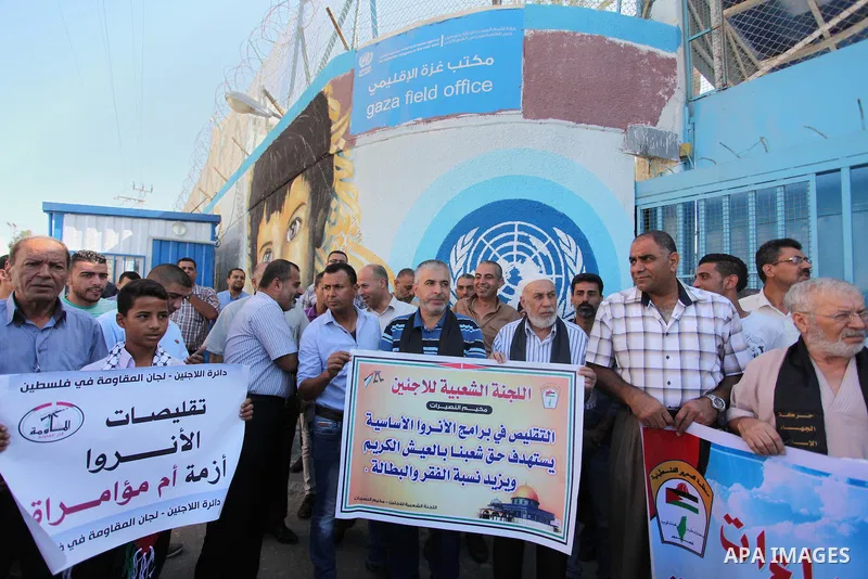 Palestinians hold banners during a protest against the UNRWA decision to reduce of the aid in front of the headquarters United Nations Relief and Works Agency (UNRWA), in Gaza city on October 11, 2016. Photo by Ashraf Am...