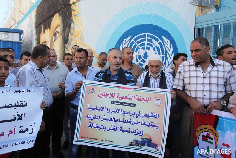 Palestinians hold banners during a protest against the UNRWA decision to reduce of the aid in front of the headquarters United Nations Relief and Works Agency (UNRWA), in Gaza city on October 11, 2016. Photo by Ashraf Am...