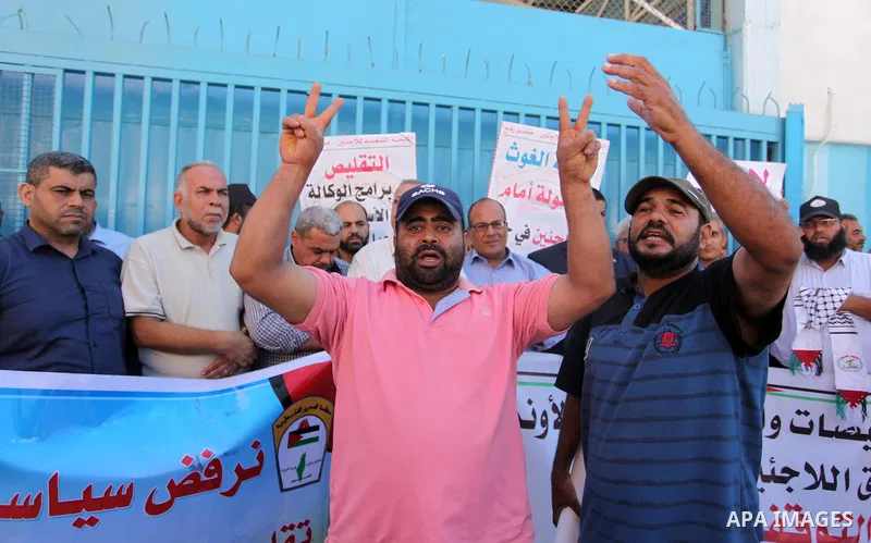 Palestinians hold banners during a protest against the UNRWA decision to reduce of the aid in front of the headquarters United Nations Relief and Works Agency (UNRWA), in Gaza city on October 11, 2016. Photo by Ashraf Am...