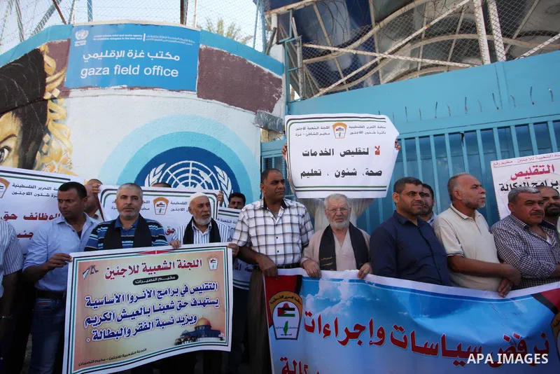 Palestinians hold banners during a protest against the UNRWA decision to reduce of the aid in front of the headquarters United Nations Relief and Works Agency (UNRWA), in Gaza city on October 11, 2016. Photo by Ashraf Am...