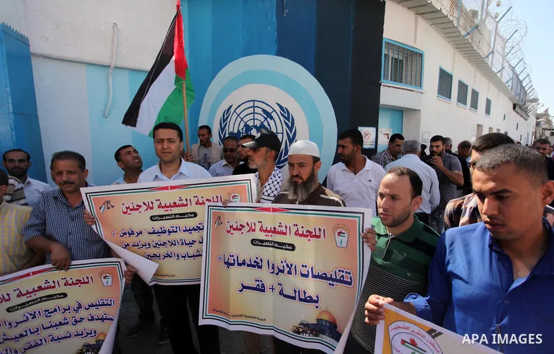 Palestinians hold banners during a protest against the UNRWA decision to reduce of the aid in front of the headquarters United Nations Relief and Works Agency (UNRWA), in Gaza city on October 11, 2016. Photo by Ashraf Am...