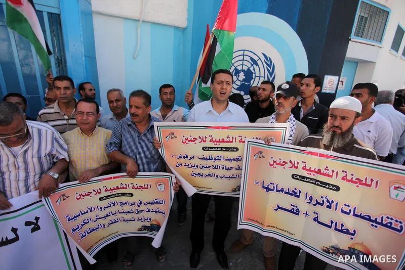 Palestinians hold banners during a protest against the UNRWA decision to reduce of the aid in front of the headquarters United Nations Relief and Works Agency (UNRWA), in Gaza city on October 11, 2016. Photo by Ashraf Am...