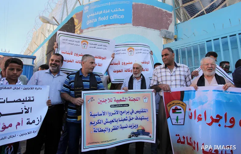 Palestinians hold banners during a protest against the UNRWA decision to reduce of the aid in front of the headquarters United Nations Relief and Works Agency (UNRWA), in Gaza city on October 11, 2016. Photo by Ashraf Am...