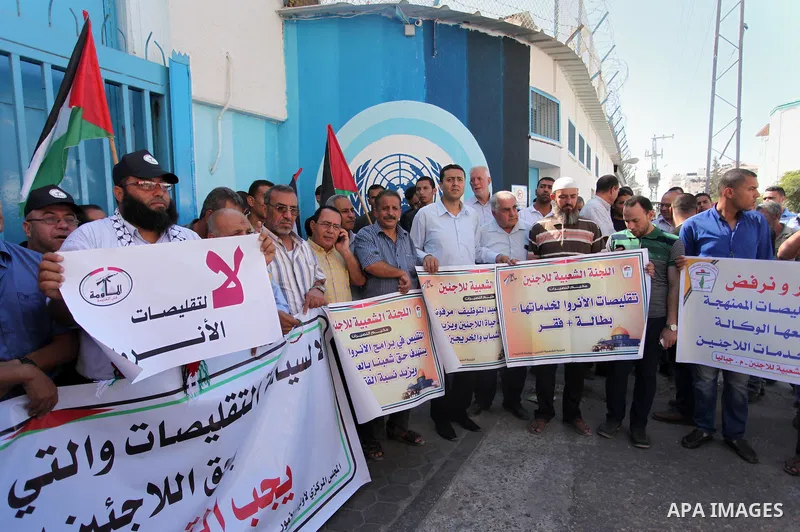 Palestinians hold banners during a protest against the UNRWA decision to reduce of the aid in front of the headquarters United Nations Relief and Works Agency (UNRWA), in Gaza city on October 11, 2016. Photo by Ashraf Am...