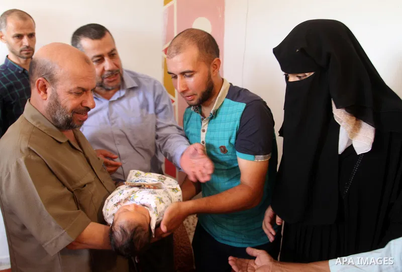 Members of the Interior Ministry in Gaza offer a certificate to Jihad and Tahany Shaath marking the birth of their son Waleed who is the two millionth baby to be born in Gaza at their house in the southern Gaza Strip tow...