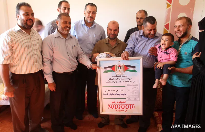 Members of the Interior Ministry in Gaza offer a certificate to Jihad and Tahany Shaath marking the birth of their son Waleed who is the two millionth baby to be born in Gaza at their house in the southern Gaza Strip tow...