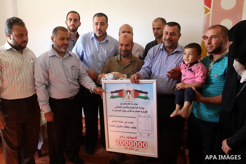 Members of the Interior Ministry in Gaza offer a certificate to Jihad and Tahany Shaath marking the birth of their son Waleed who is the two millionth baby to be born in Gaza at their house in the southern Gaza Strip tow...
