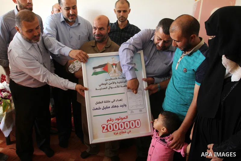 Members of the Interior Ministry in Gaza offer a certificate to Jihad and Tahany Shaath marking the birth of their son Waleed who is the two millionth baby to be born in Gaza at their house in the southern Gaza Strip tow...