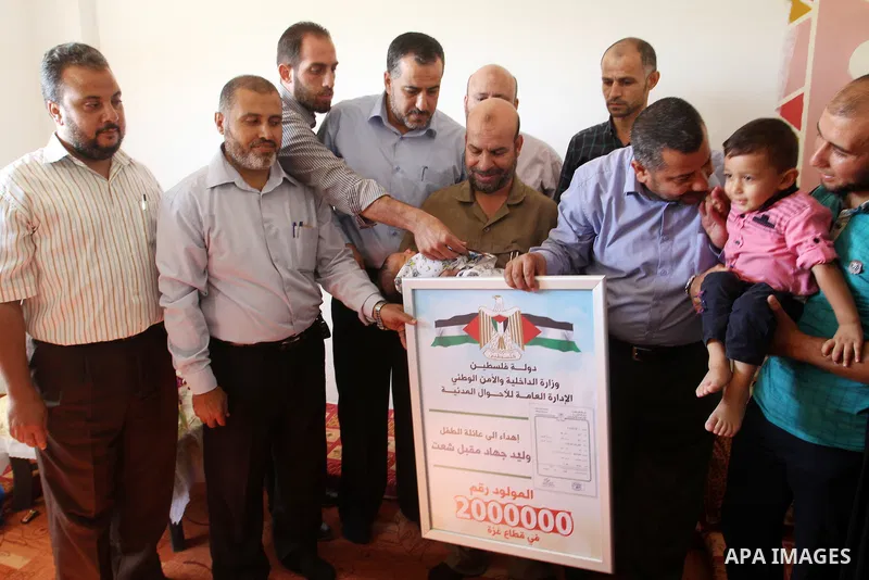 Members of the Interior Ministry in Gaza offer a certificate to Jihad and Tahany Shaath marking the birth of their son Waleed who is the two millionth baby to be born in Gaza at their house in the southern Gaza Strip tow...