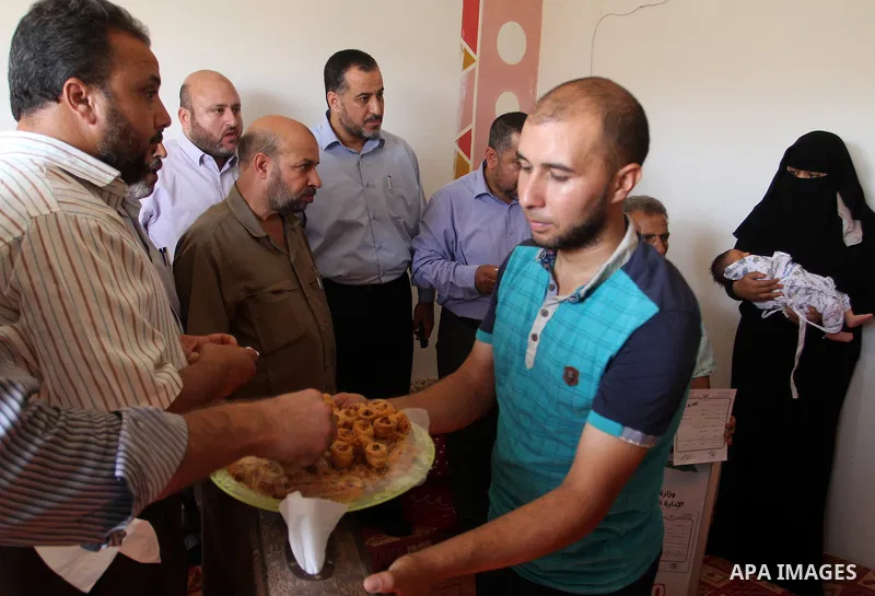 Members of the Interior Ministry in Gaza offer a certificate to Jihad and Tahany Shaath marking the birth of their son Waleed who is the two millionth baby to be born in Gaza at their house in the southern Gaza Strip tow...