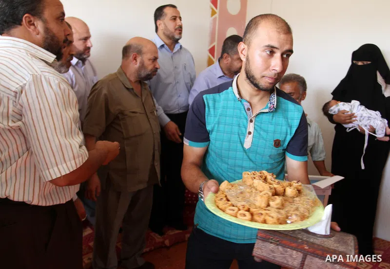 Members of the Interior Ministry in Gaza offer a certificate to Jihad and Tahany Shaath marking the birth of their son Waleed who is the two millionth baby to be born in Gaza at their house in the southern Gaza Strip tow...