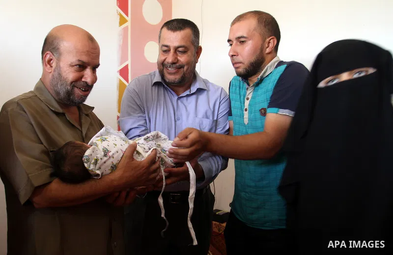 Members of the Interior Ministry in Gaza offer a certificate to Jihad and Tahany Shaath marking the birth of their son Waleed who is the two millionth baby to be born in Gaza at their house in the southern Gaza Strip tow...