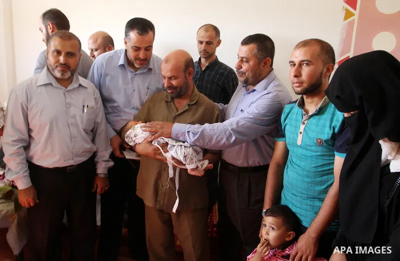 Members of the Interior Ministry in Gaza offer a certificate to Jihad and Tahany Shaath marking the birth of their son Waleed who is the two millionth baby to be born in Gaza at their house in the southern Gaza Strip tow...