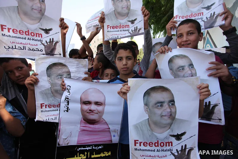 Palestinian boys hold posters of Mohammad El Halabi, World Vision's manager of operations in Gaza who was accused by Israel of funnelling millions of dollars in aid money to Hamas, during a protest in solidarity with El...
