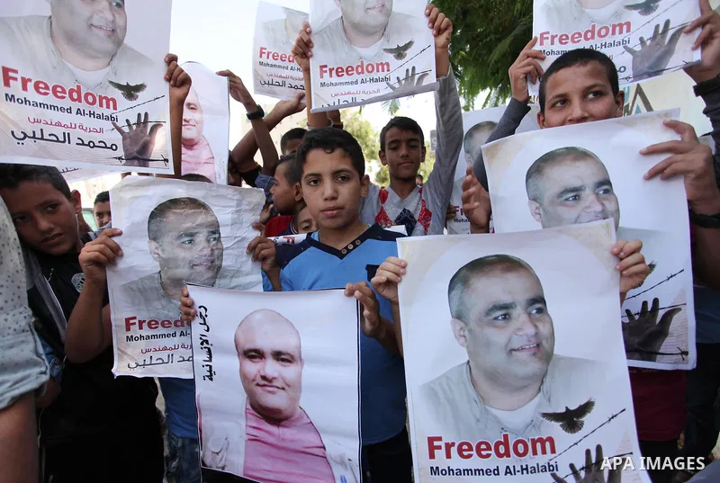 Palestinian boys hold posters of Mohammad El Halabi, World Vision's manager of operations in Gaza who was accused by Israel of funnelling millions of dollars in aid money to Hamas, during a protest in solidarity with El...