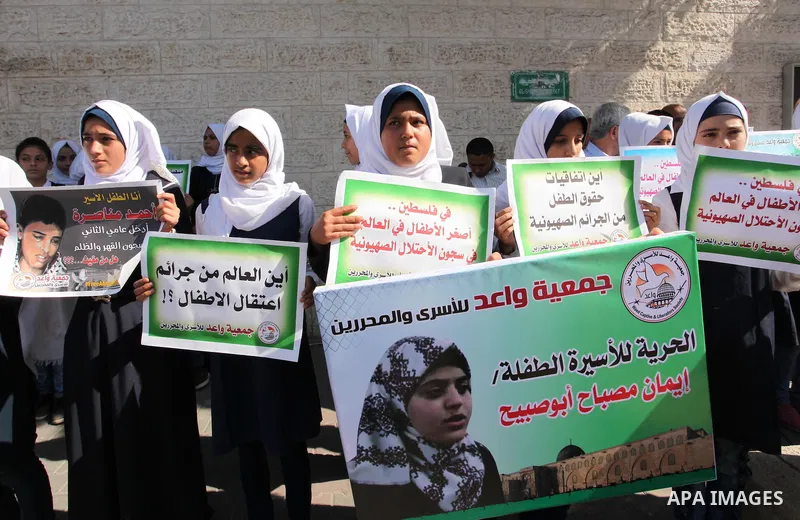 Palestinian students hold banners during a protest to show solidarity with the child prisoners in Israeli jails, in front of Red cross office in Gaza city, on October 13, 2016. Photo by Ashraf Amra