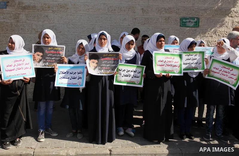 Palestinian students hold banners during a protest to show solidarity with the child prisoners in Israeli jails, in front of Red cross office in Gaza city, on October 13, 2016. Photo by Ashraf Amra