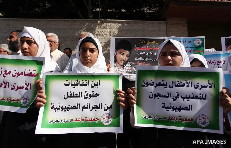 Palestinian students hold banners during a protest to show solidarity with the child prisoners in Israeli jails, in front of Red cross office in Gaza city, on October 13, 2016. Photo by Ashraf Amra