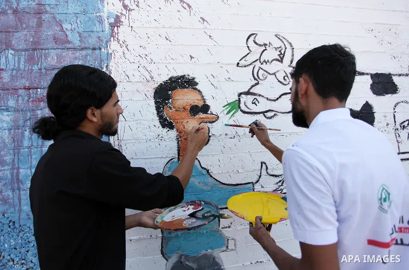 Palestinian artists paint a mural during a rally marking World Peace Day, in the port of Gaza city, on October 13, 2016. Photo by Ashraf Amra