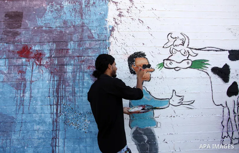 A Palestinian artist paints a mural during a rally marking World Peace Day, in the port of Gaza city, on October 13, 2016. Photo by Ashraf Amra